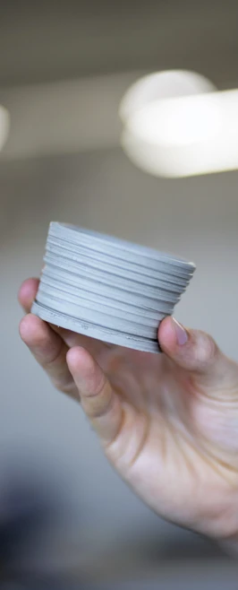 Hand holding a small, unfinished ceramic pot or clay object in a studio setting. Hand holding a small, unfinished ceramic pot or clay object in a studio setting.